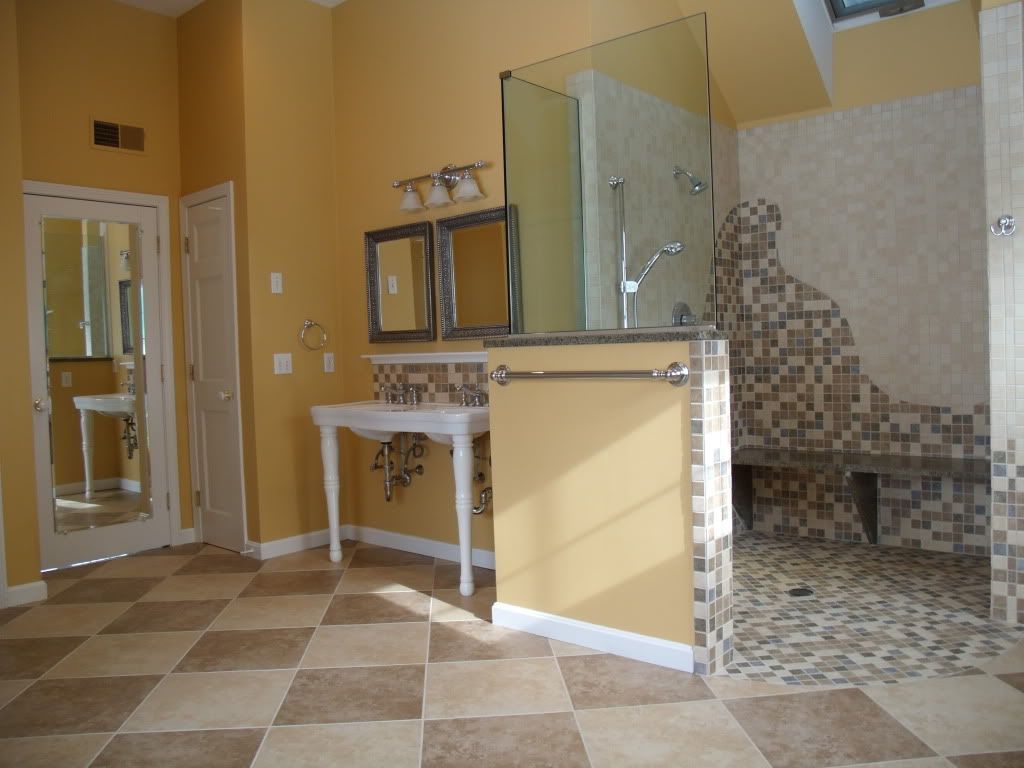 Spacious bathroom with beige and brown checkered floor. Features a shower, vanity, and large mirrors against yellow walls.