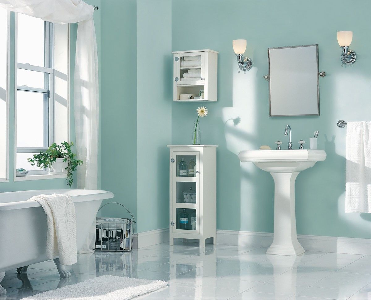 Bright blue bathroom with white fixtures, a claw-foot tub, and a window with sheer curtains.