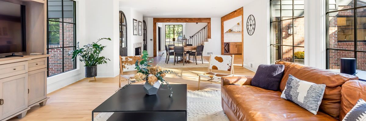 Living room with leather sofa, black coffee table, and large windows.