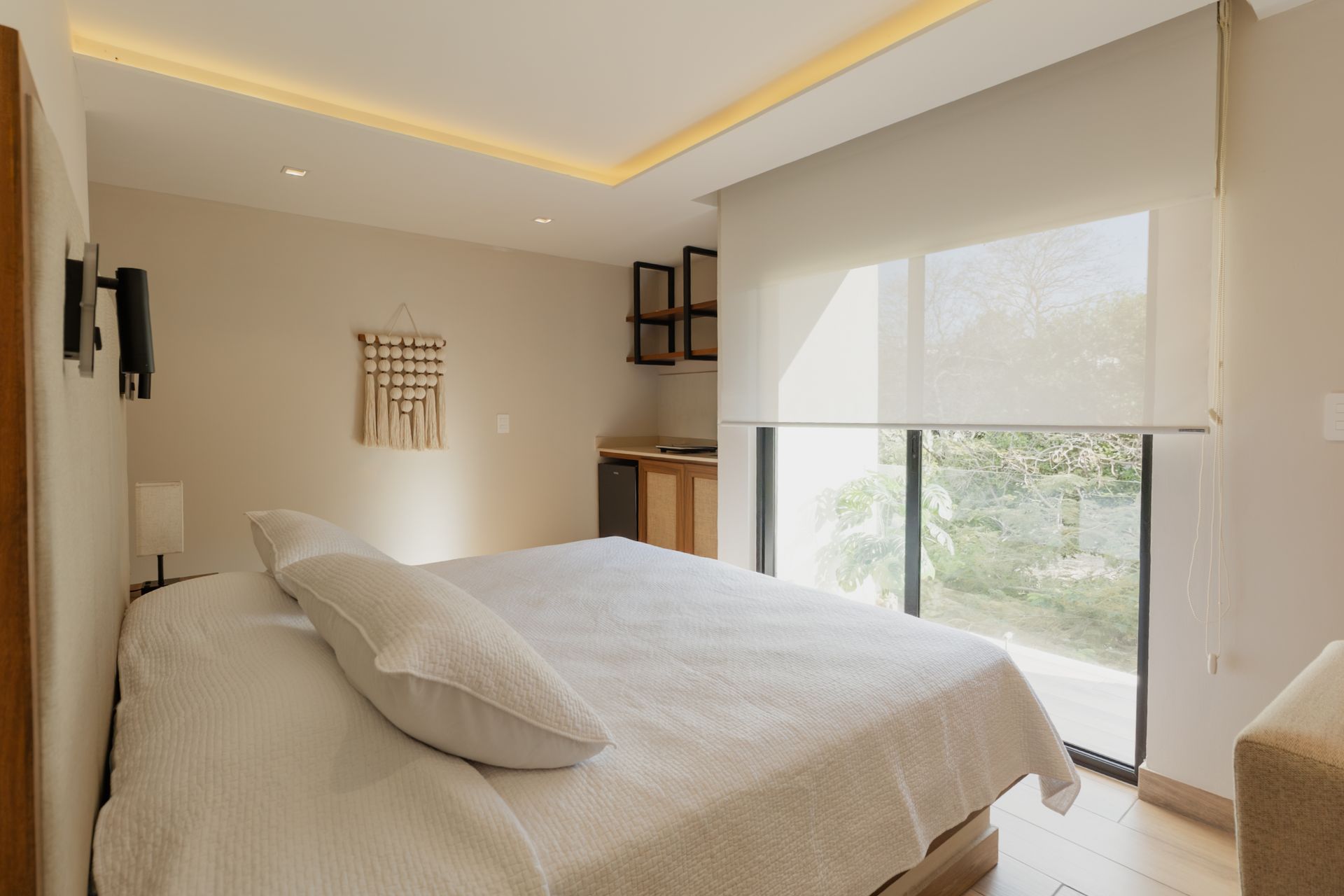 Habitación luminosa y moderna con cama, escritorio, armario con espejo y grandes cortinas.