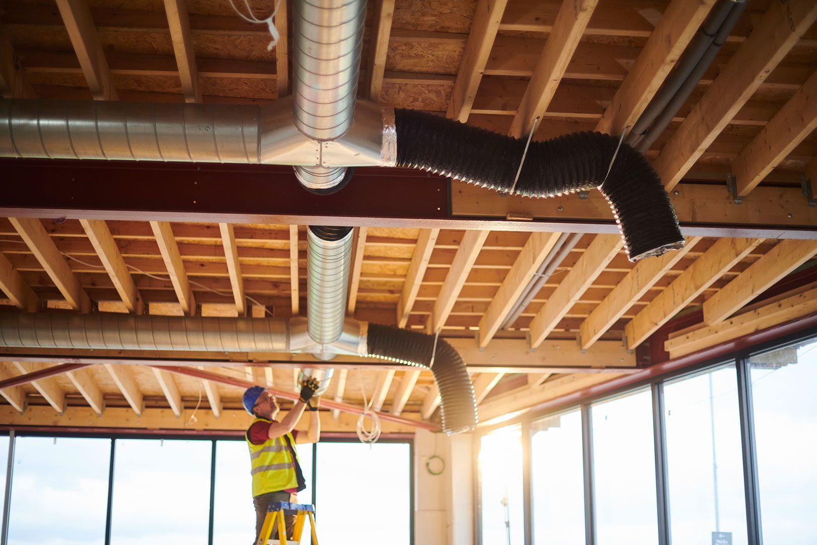 A construction worker is working on the ceiling of a building.