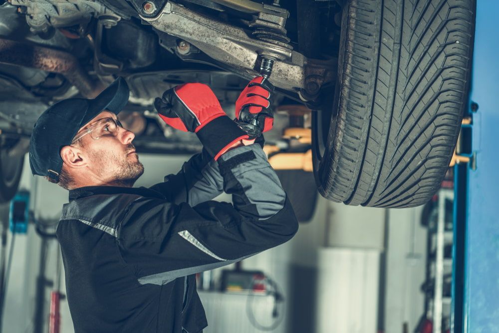 A Man is Working on the Underside of a Car in a Garage — Brittle's Family Auto Centre in Sunshine Coast, QLD