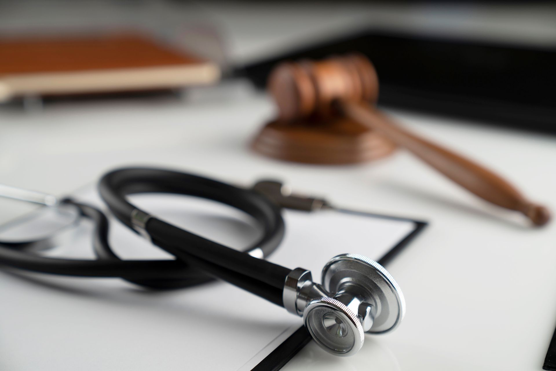 A black stethoscope laying in front of a wooden gavel