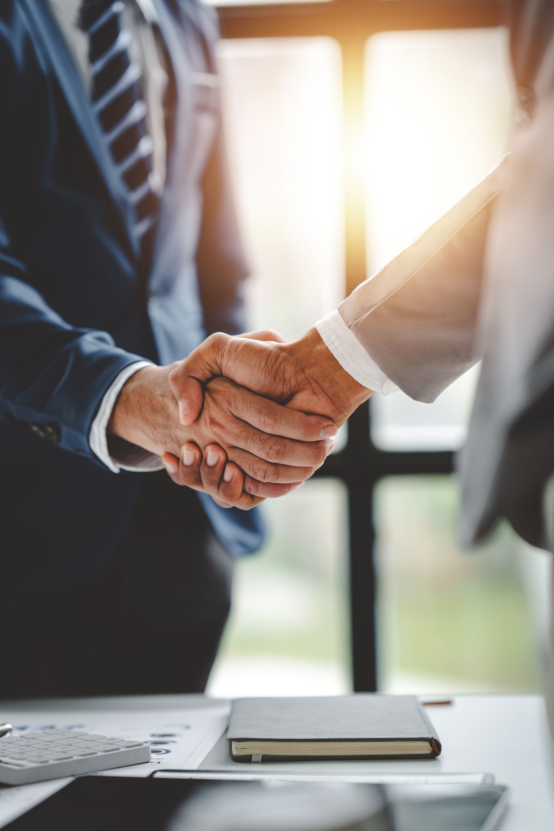 Two people wearing suits and shaking each other's hands