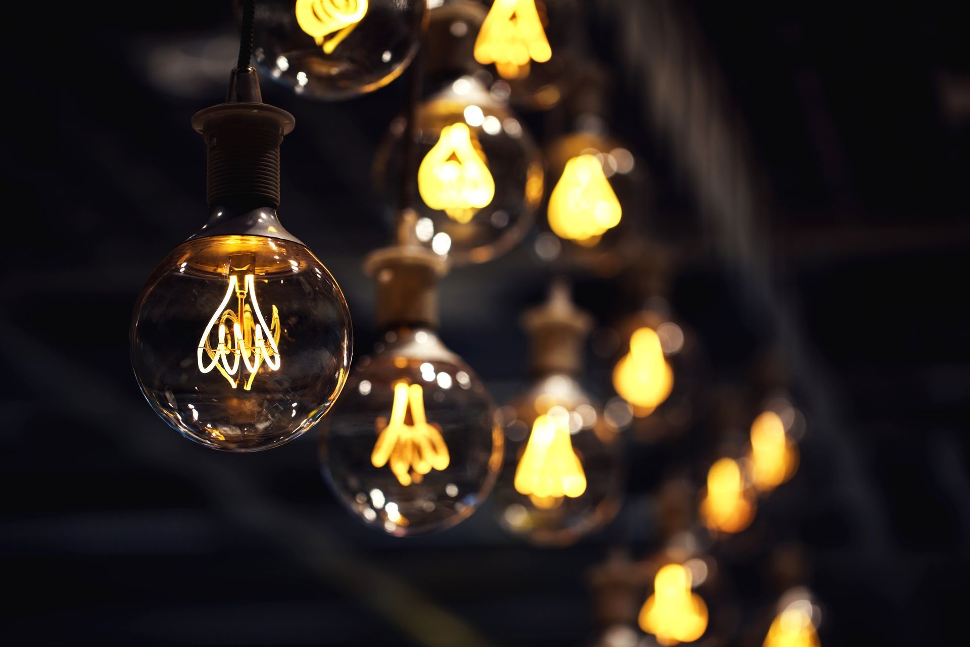 Glowing Edison light bulbs hanging from a ceiling, creating a warm, dim atmosphere.