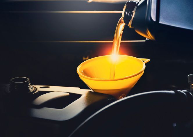 Mechanic man pouring lubricant oil to car engine — A Grade Oils & Batteries In Wodonga VIC