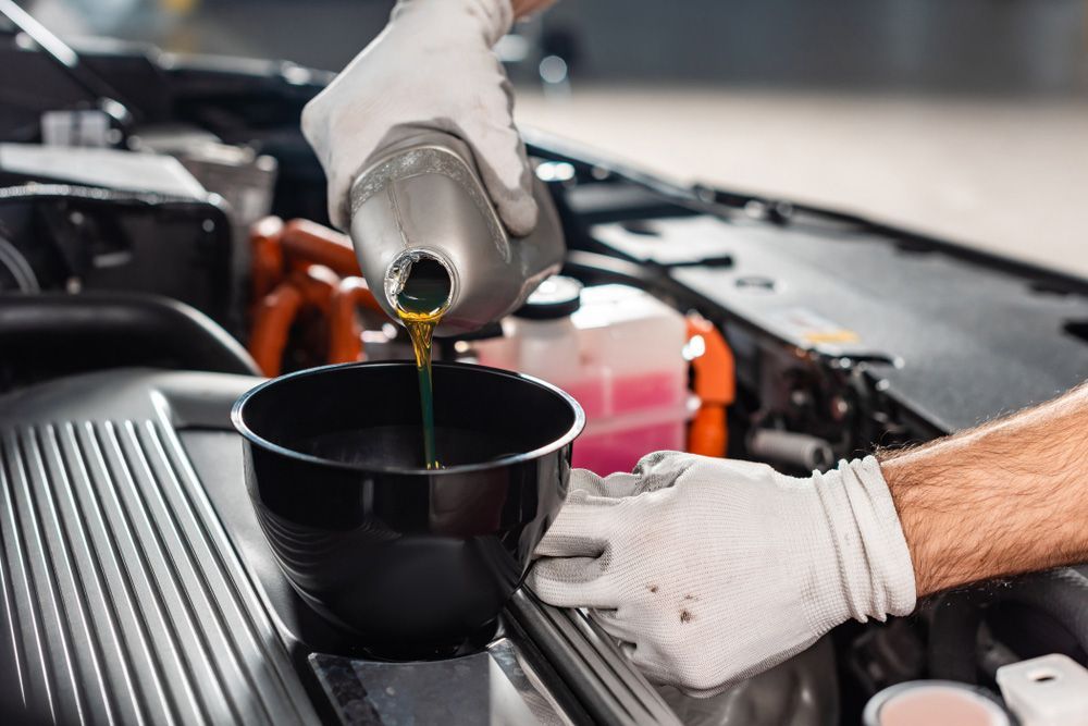 Cropped view of mechanic pouring oil to car engine — A Grade Oils & Batteries In Wodonga VIC