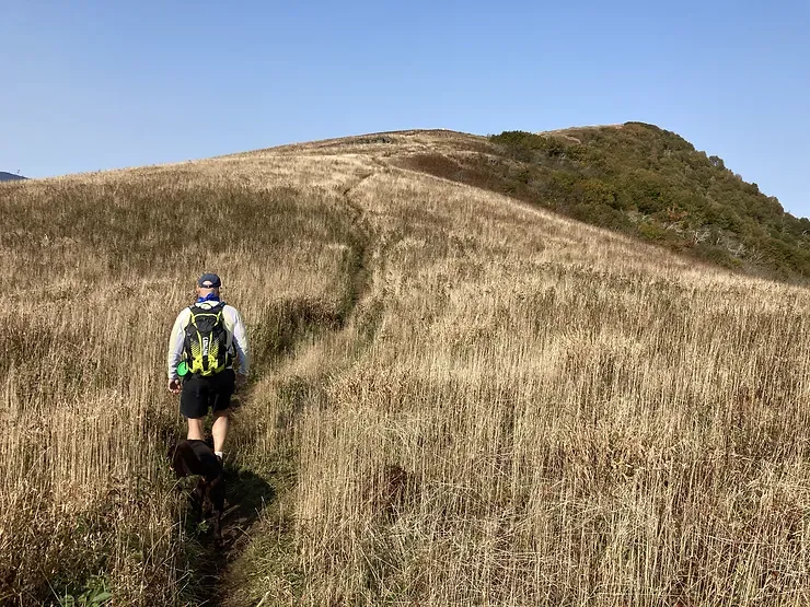 A person with a backpack is walking up a hill.