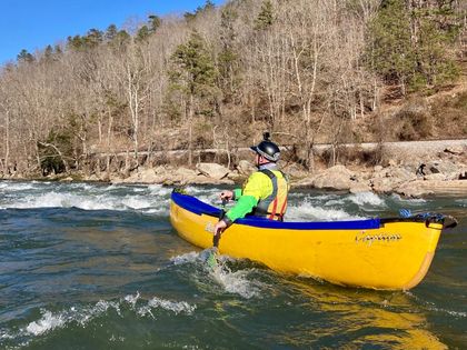 A man is riding a yellow kayak down a river.