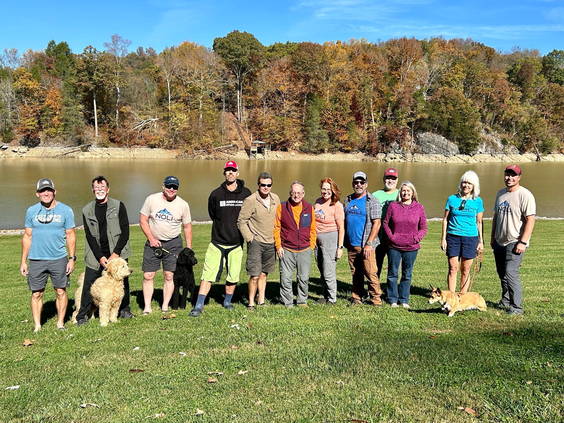 A group of people are posing for a picture in a room with a man wearing a noli shirt.