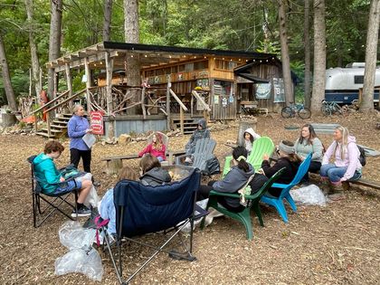 A group of people are sitting around a fire pit in the woods.