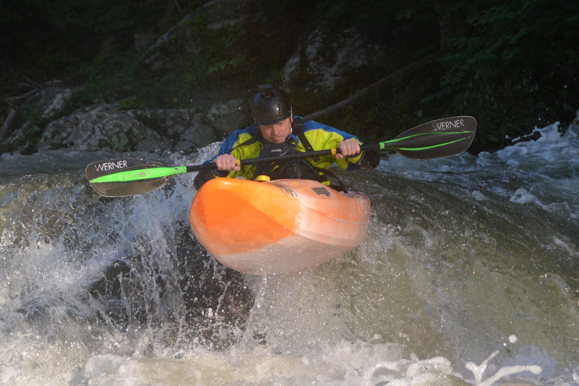 A man is riding a kayak down a river.