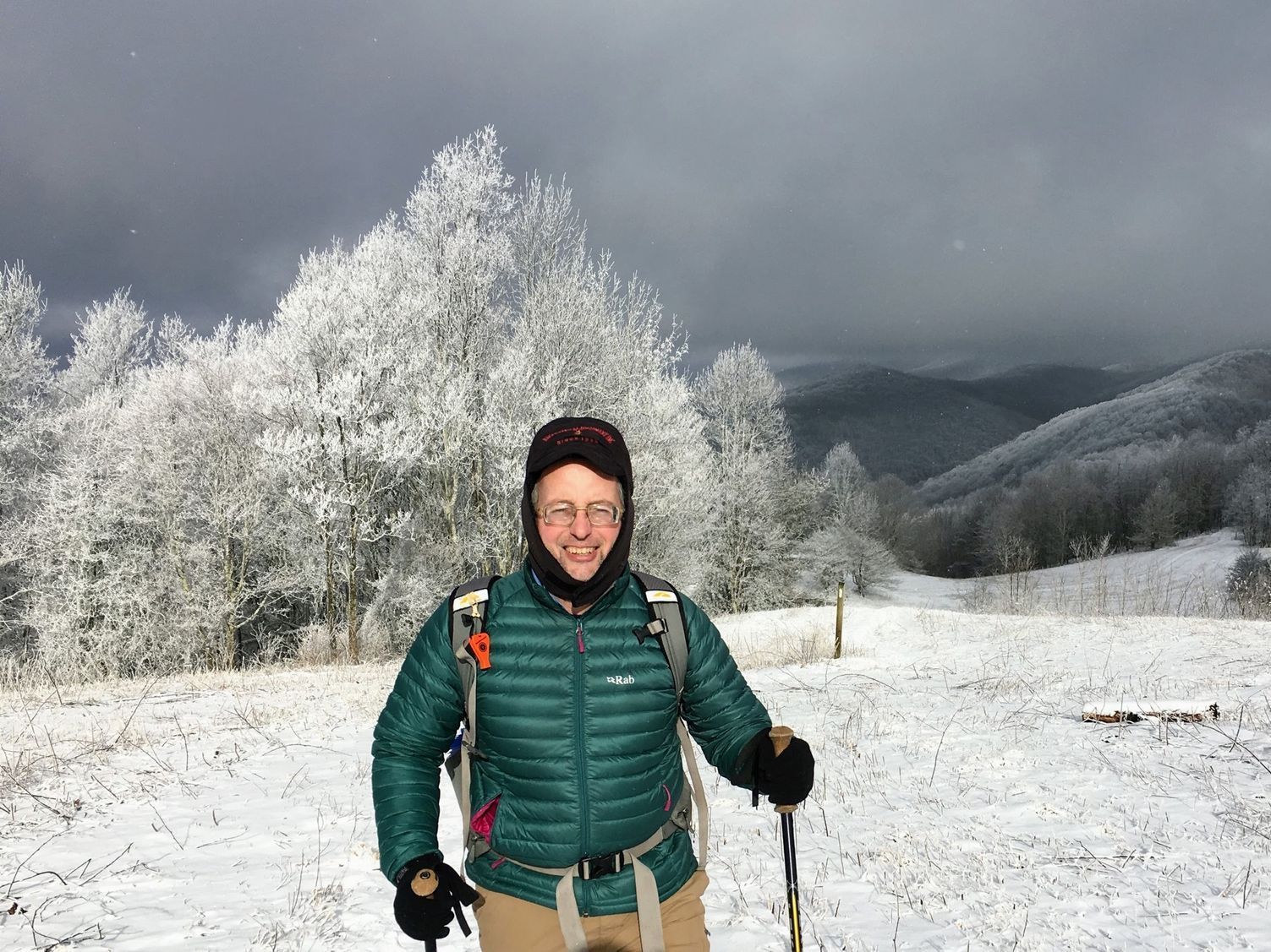 A man in a green jacket is standing in the snow.