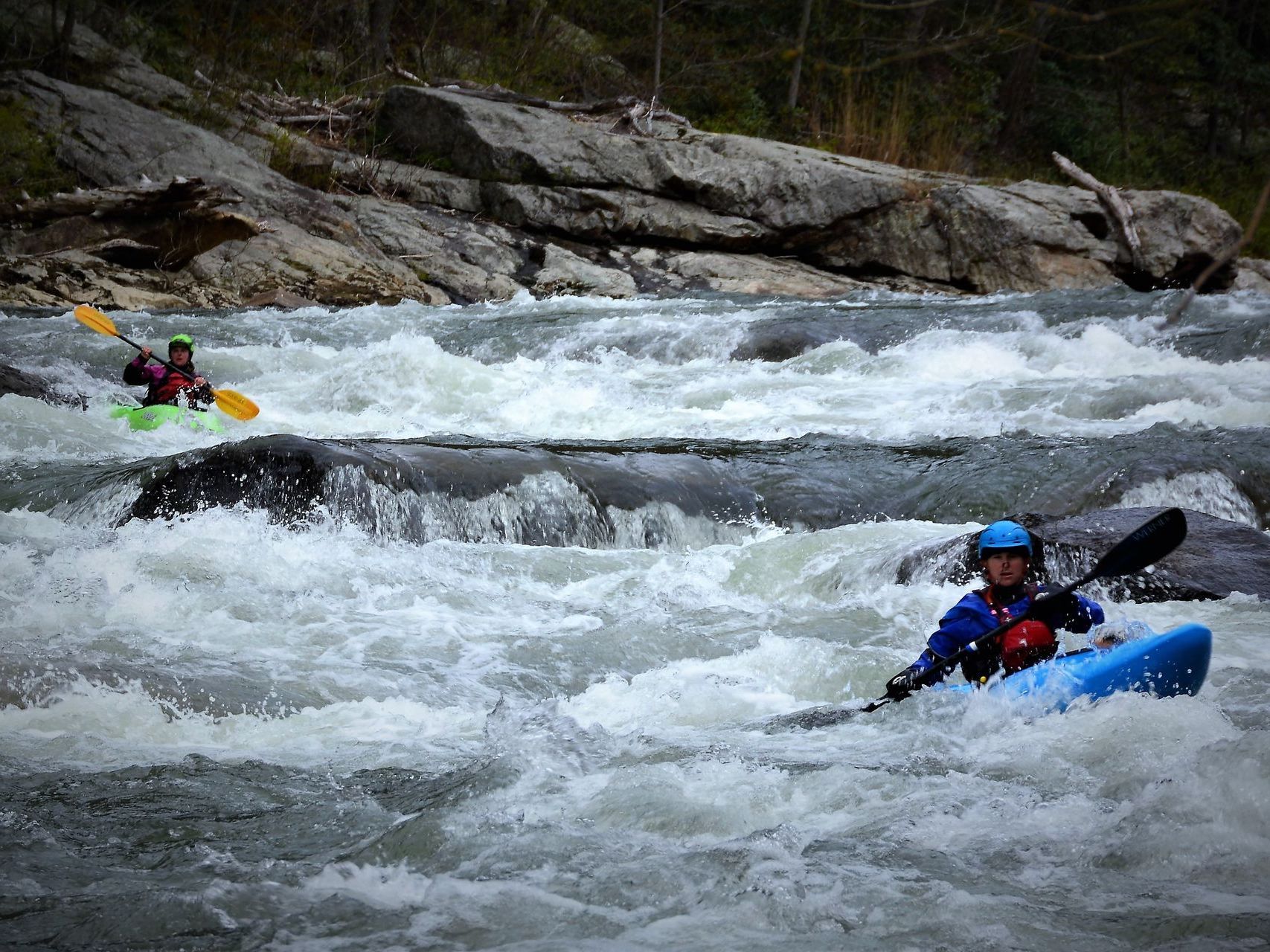 A couple of people are kayaking down a river.