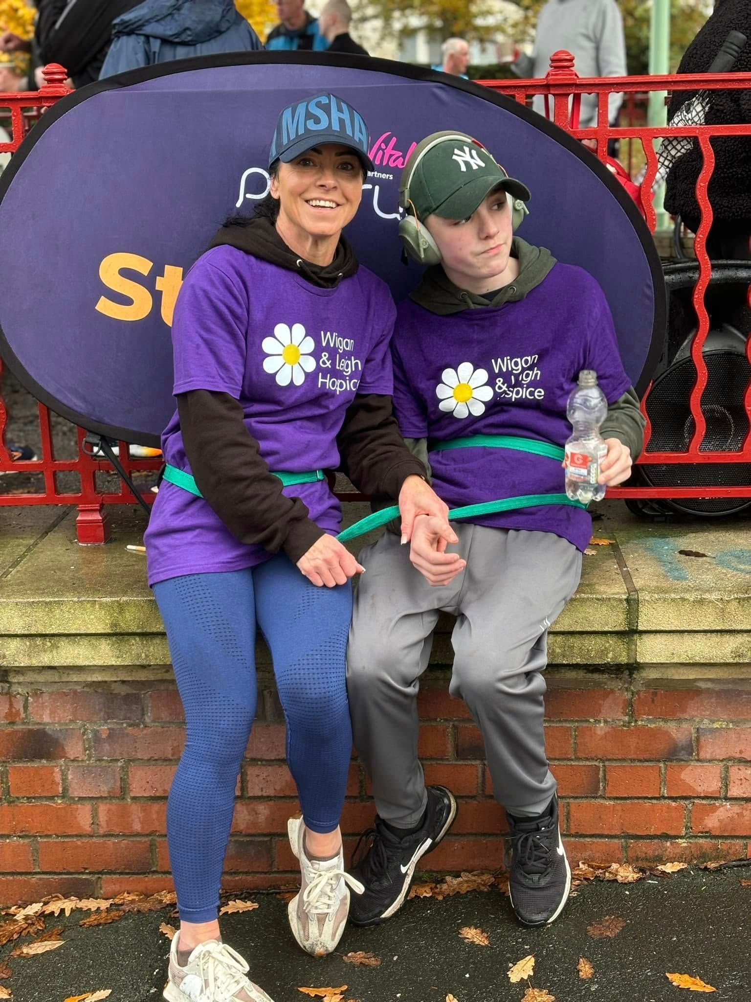 A woman and a boy are sitting next to each other on a brick wall.