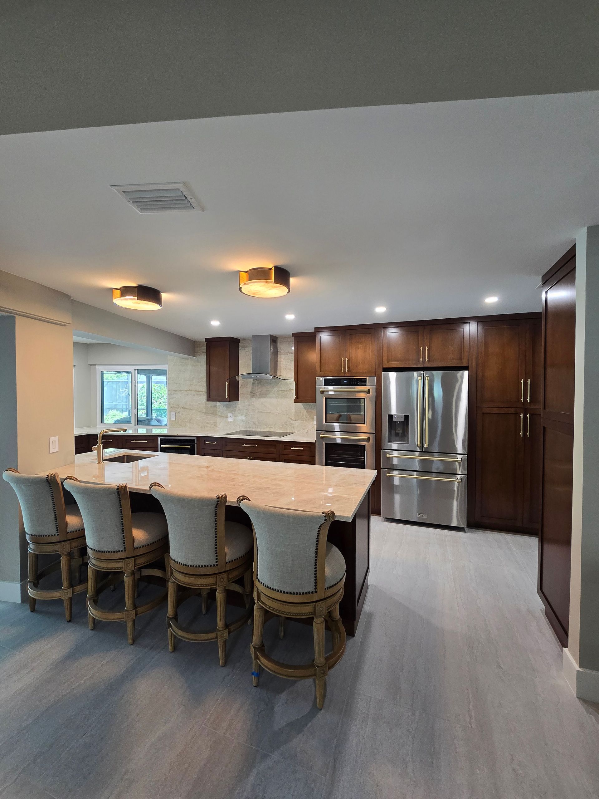 Modern kitchen with dark wood cabinets, a granite island with four bar stools. Available in Lithia