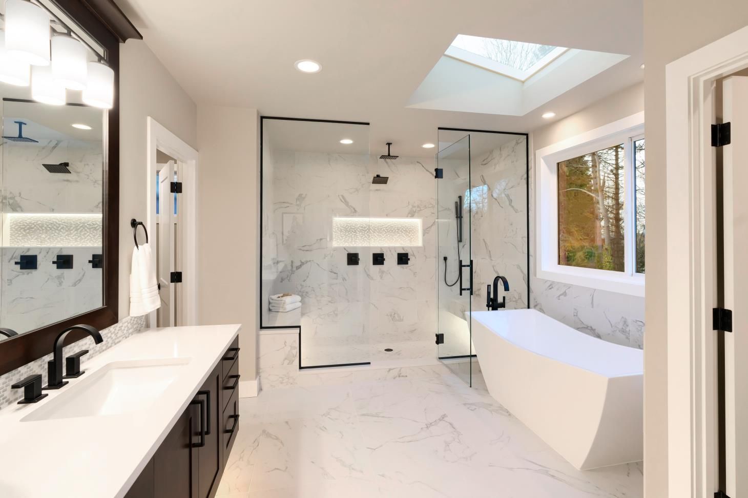 a bathroom with two sinks , a tub , a shower and a skylight .