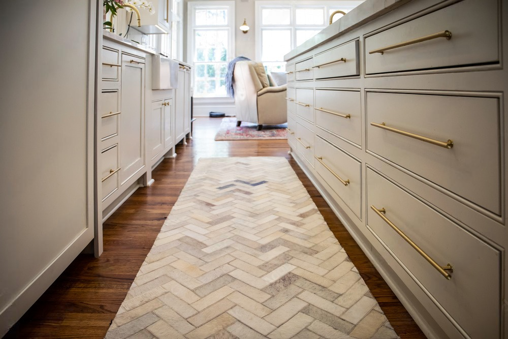 a kitchen with white cabinets and a herringbone rug on the floor .