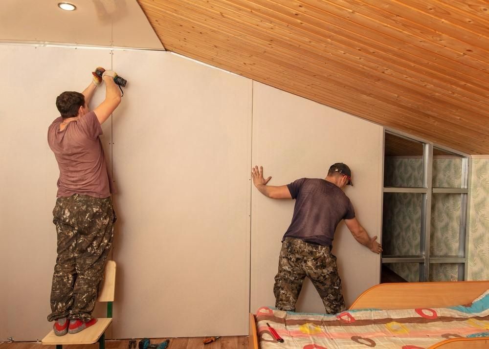 two men are working on a wall in a bedroom .