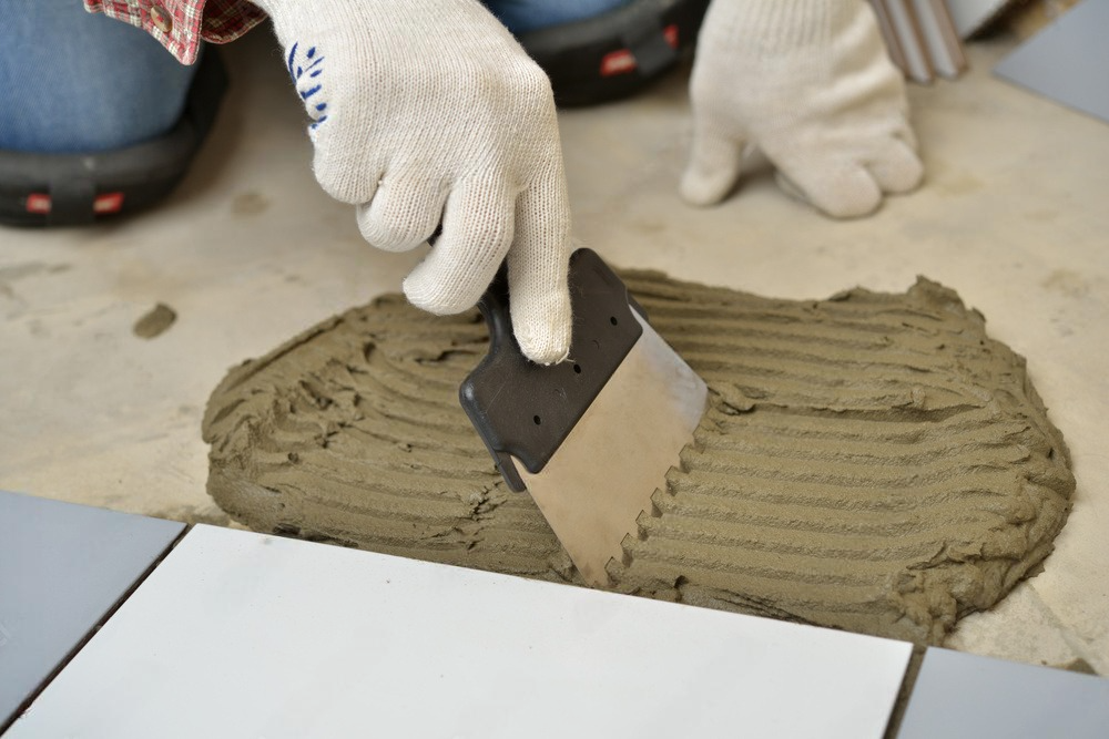 a person is applying adhesive to a tile with a spatula .