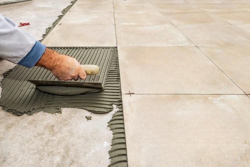 a man is laying tiles on a floor with a trowel .