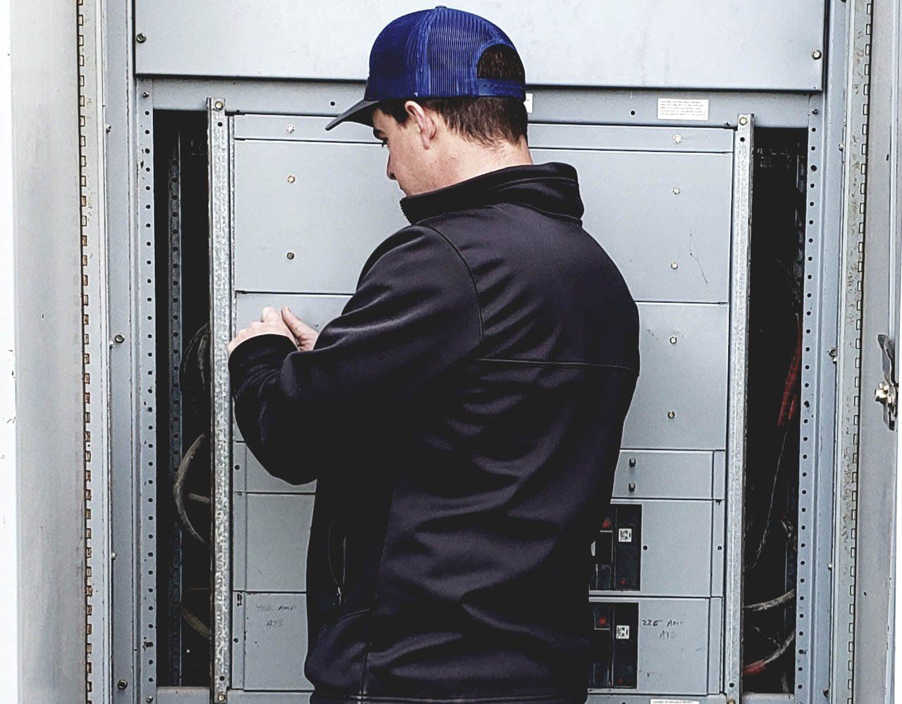 A professional electrician works on an electrical panel breaker box