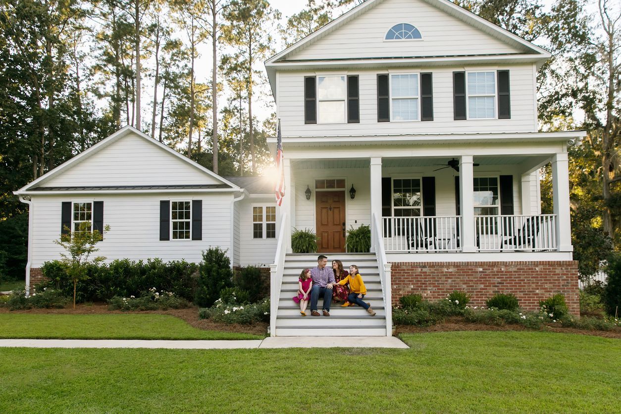 A family is sitting on the steps of their house.