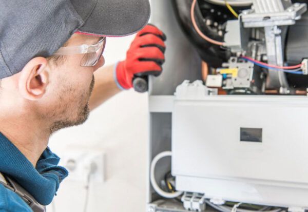 A man is working on a boiler with a flashlight.