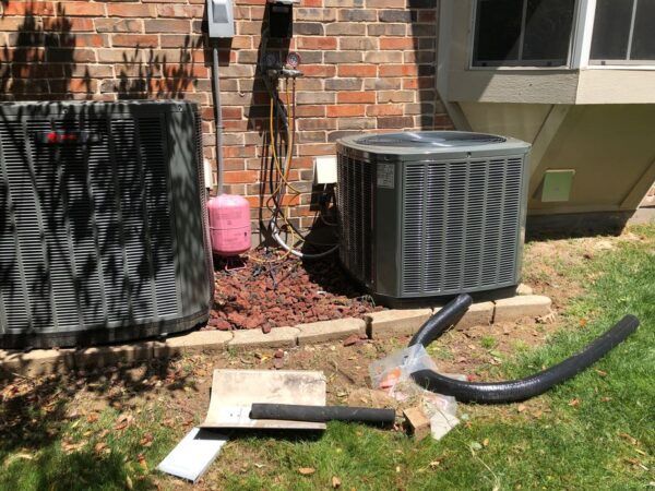 Two air conditioners are sitting on the side of a brick building.