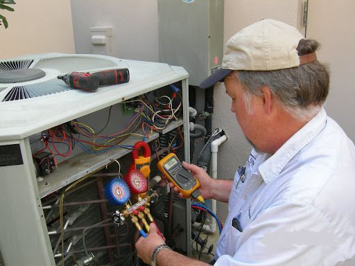 A man is working on an air conditioner with a digital thermometer.