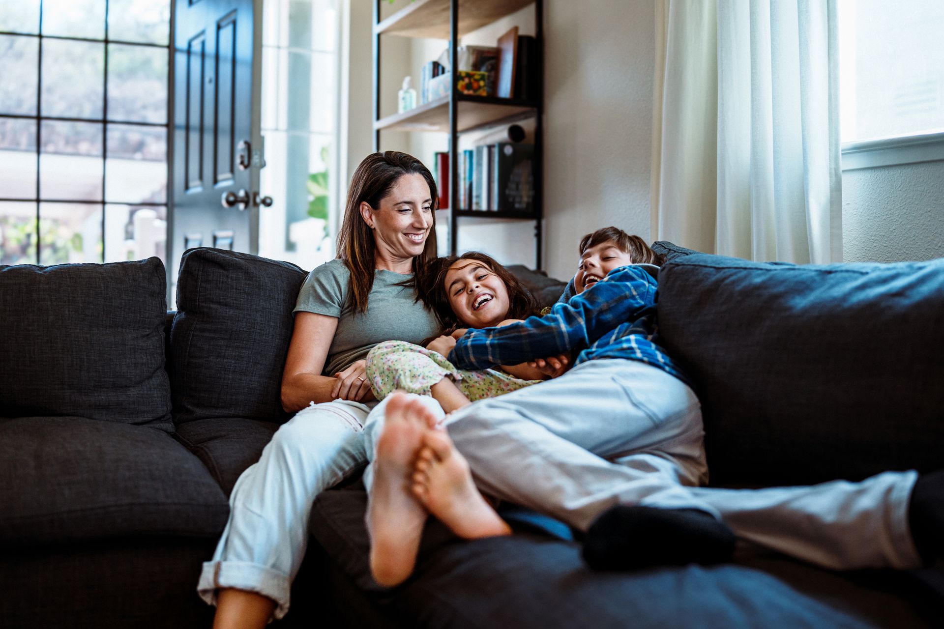 Playful kids on the couch with their mom in a Jupiter, Florida home.