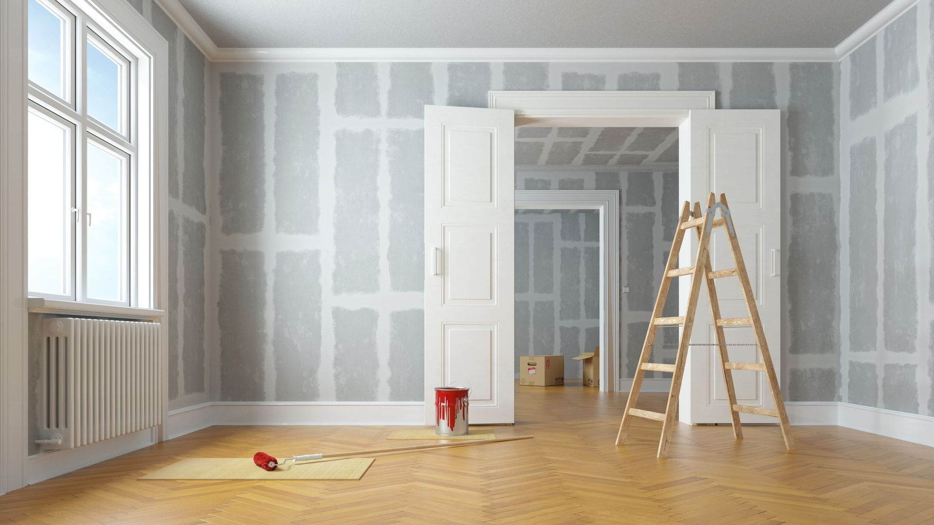 An empty room with a ladder and a bucket of paint.