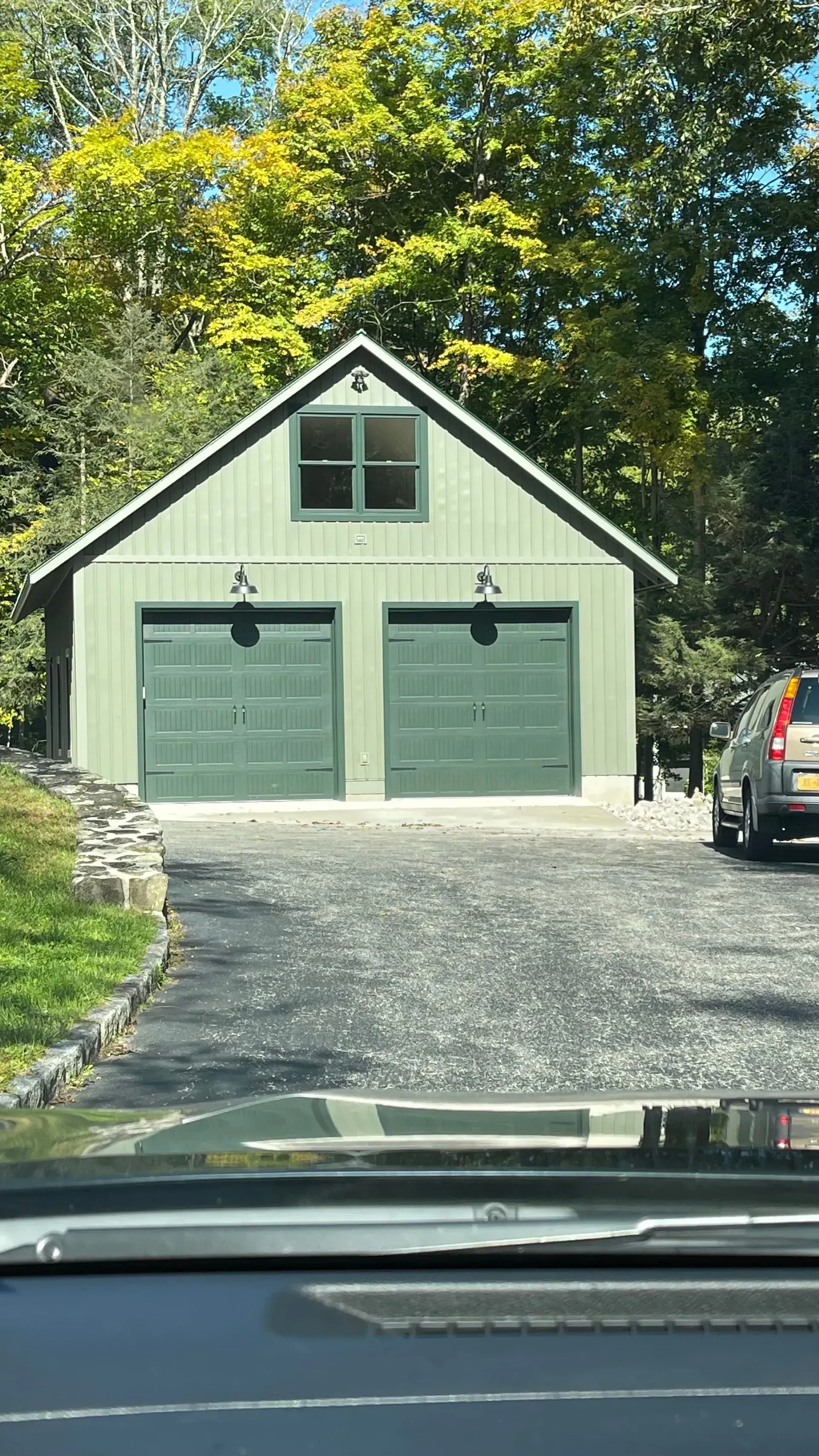 A car is parked in front of a green garage.