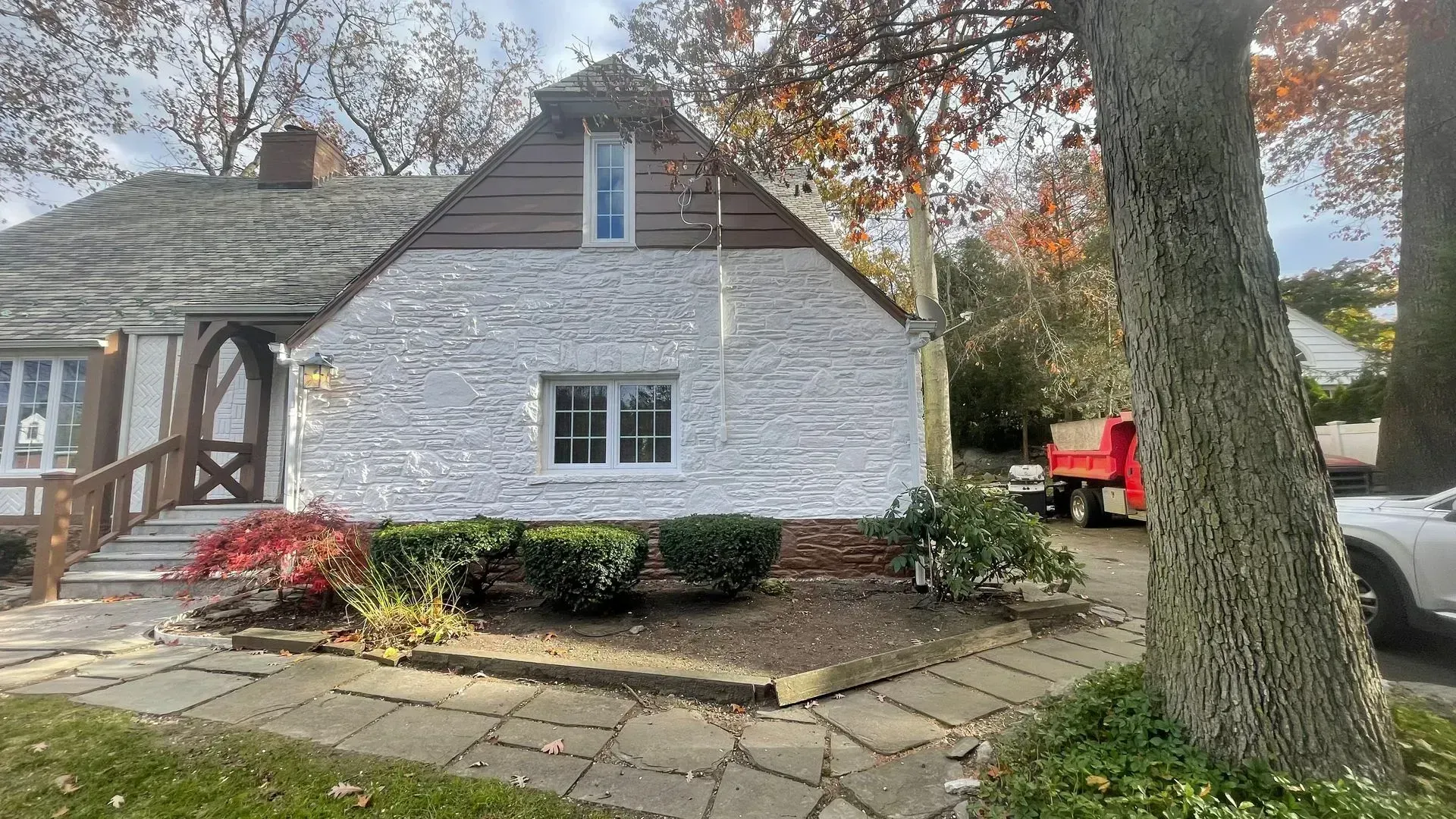 A white house with a red truck parked in front of it.