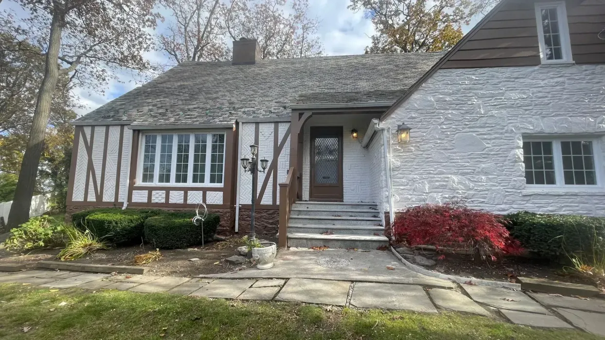 A white brick house with a brown roof is for sale.