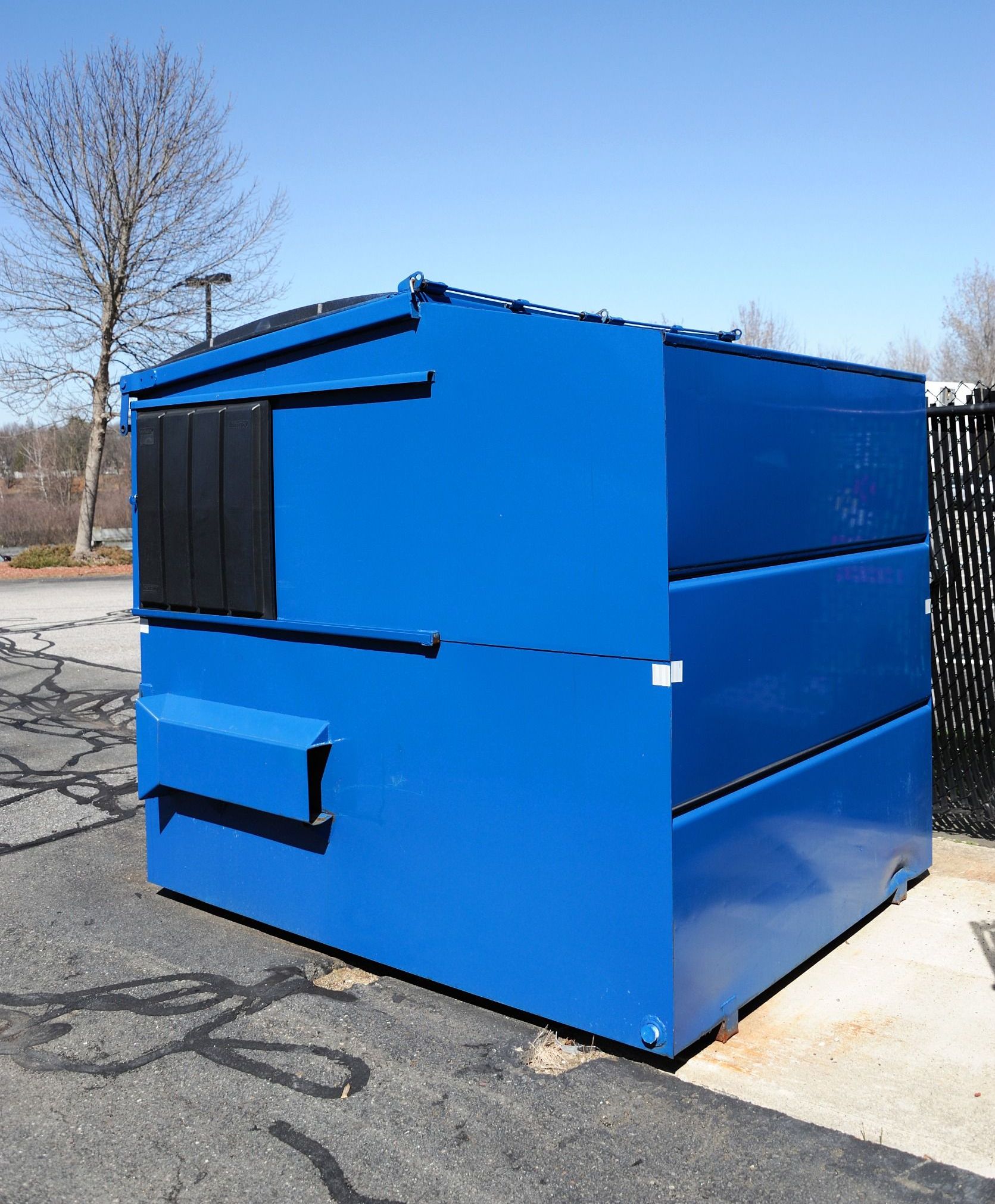 A blue dumpster is sitting on the side of the road