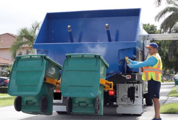 A man is standing in front of a garbage truck