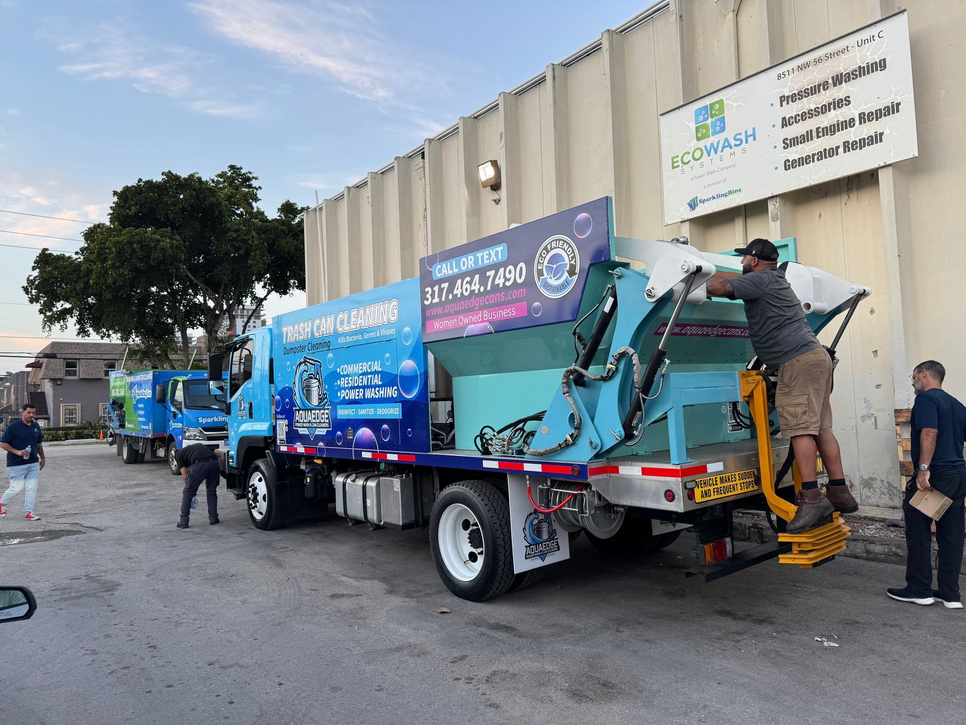 A man and a little girl are putting trash into a green trash can.