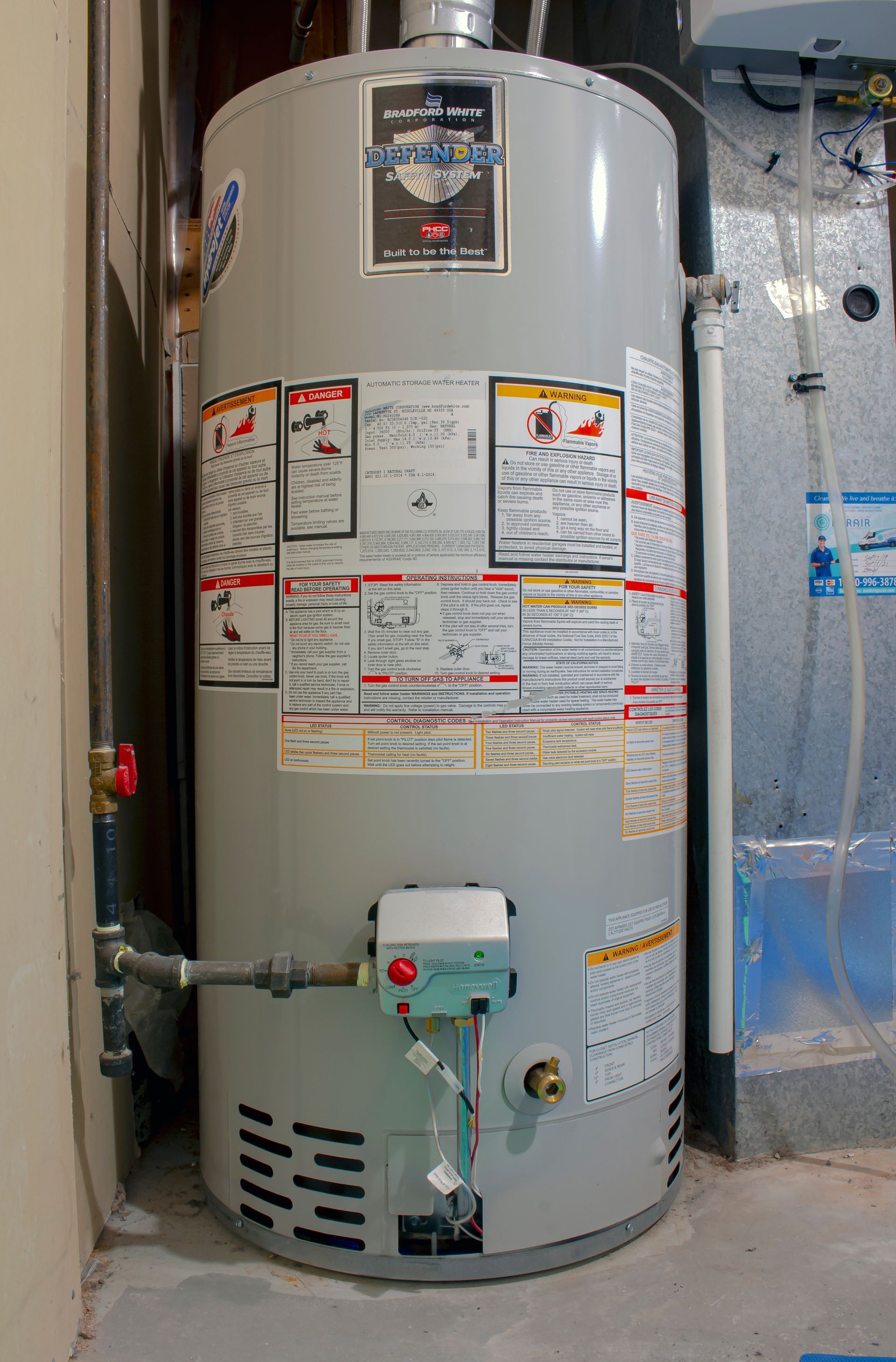 Large beige water heater with warning labels in a utility room