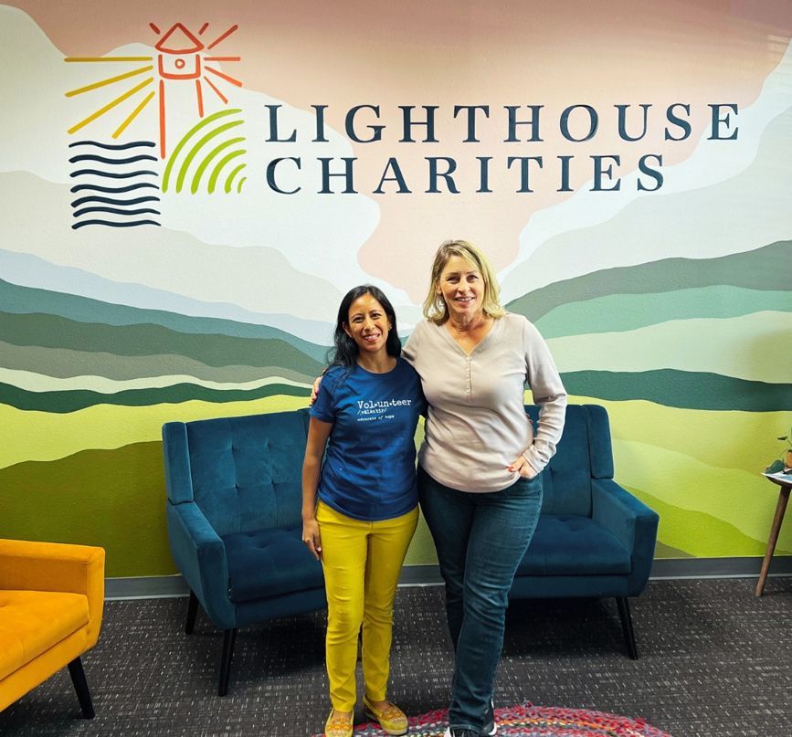 Two women pose in front of a wall with