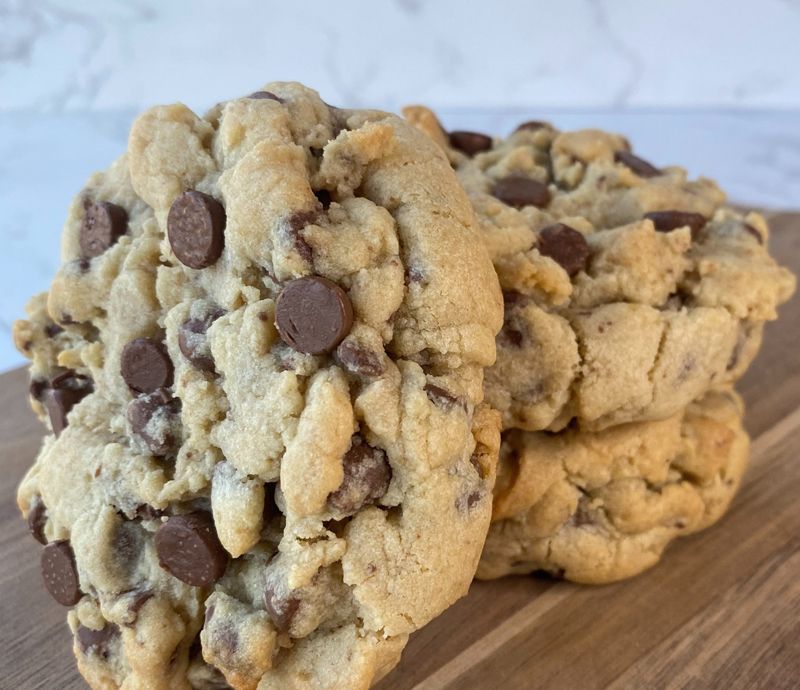 Pile of chocolate chip cookies on a wooden board; close-up.