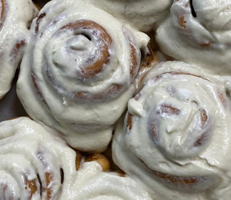 Cinnamon rolls, swirled and covered in white frosting.