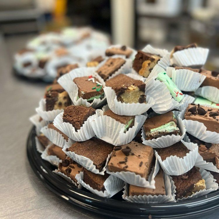 Brownie bites on a black tray, some with chocolate chips and toppings.