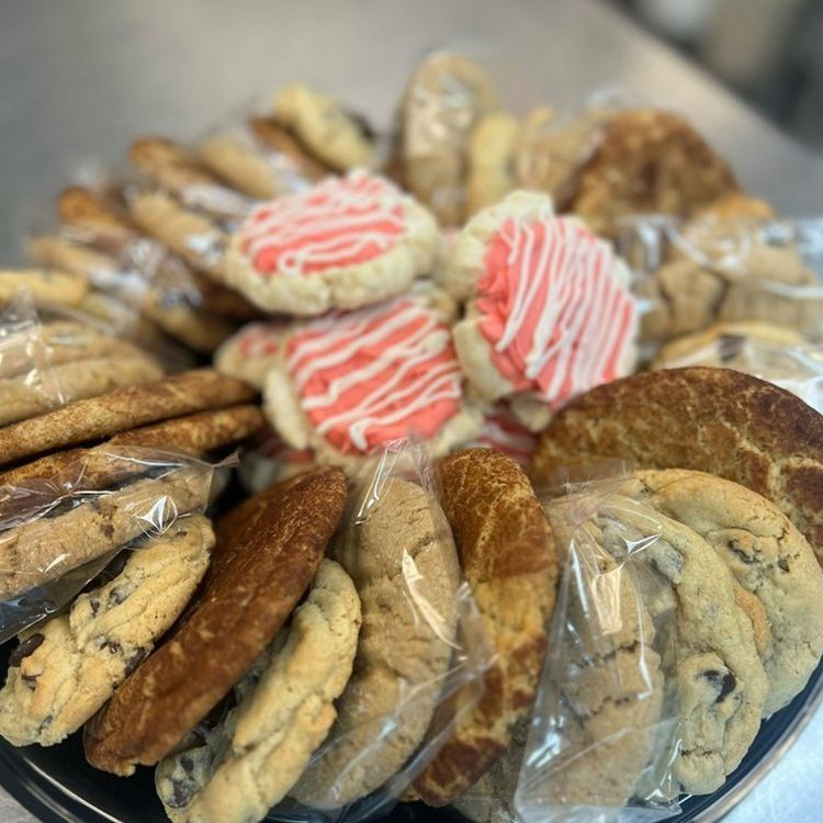 A tray of assorted cookies, some individually wrapped. Includes chocolate chip, frosted, and other varieties.
