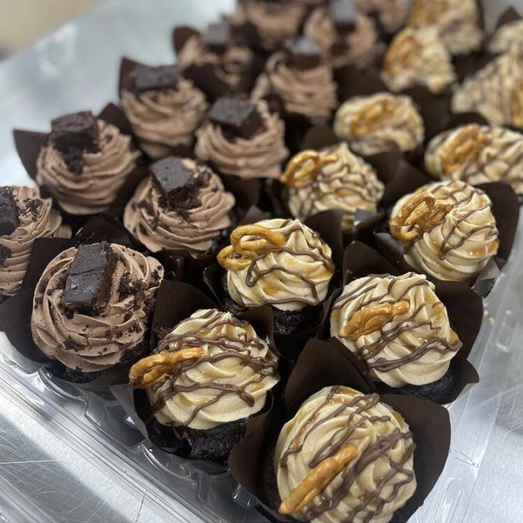 Tray of chocolate cupcakes with chocolate and caramel toppings, close-up shot.