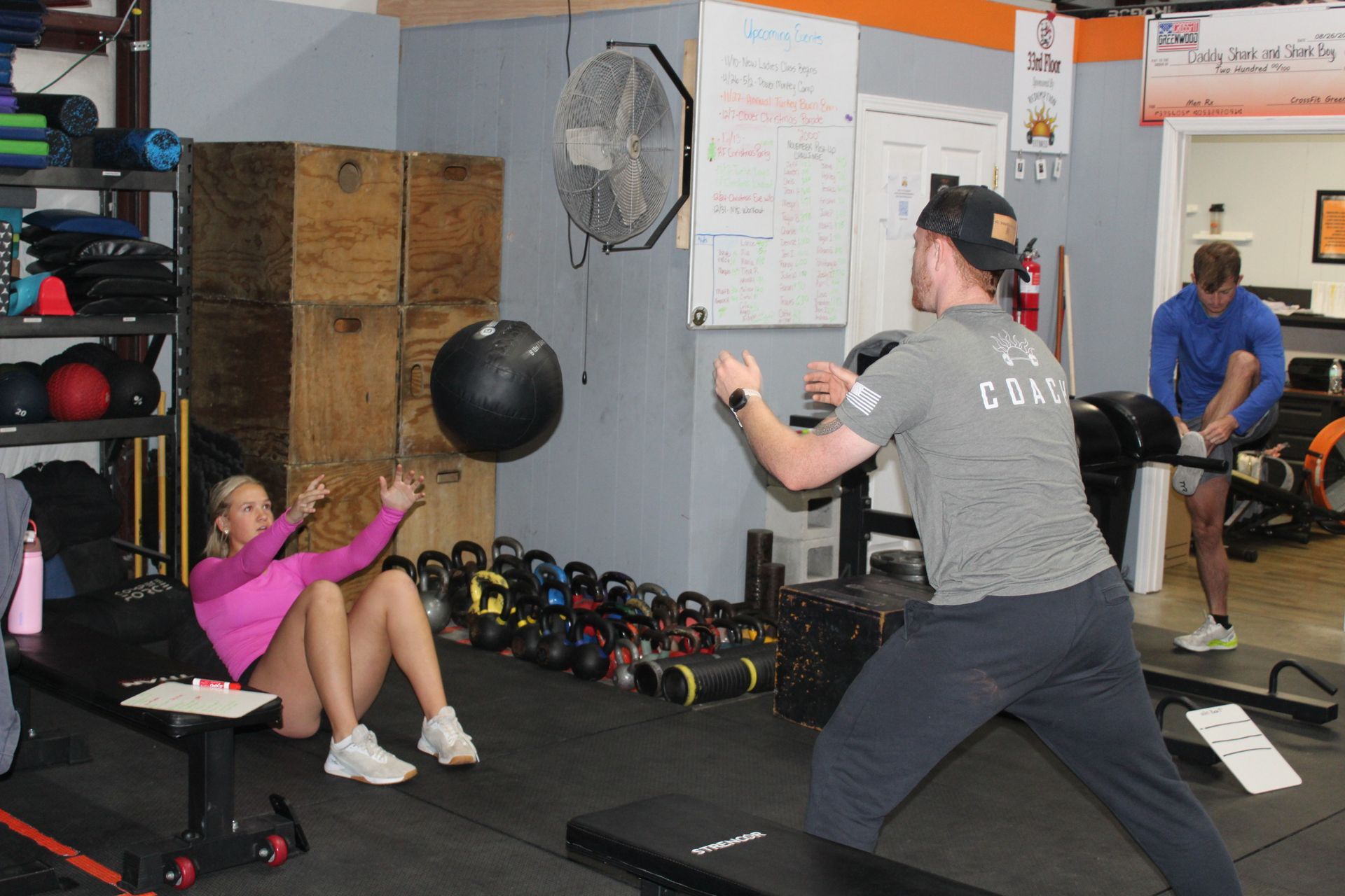 People exercising in a gym, doing medicine ball and bodyweight workouts.