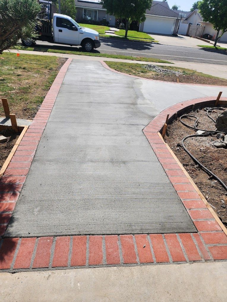A white truck is parked on the side of a concrete driveway.