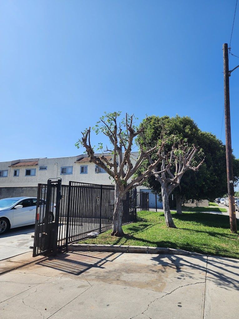 A car is parked in front of a building next to a fence.