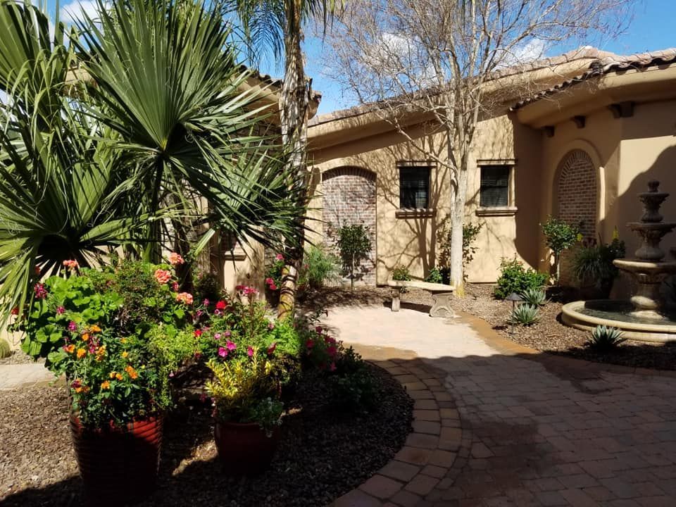 A house with a fountain and flowers in front of it