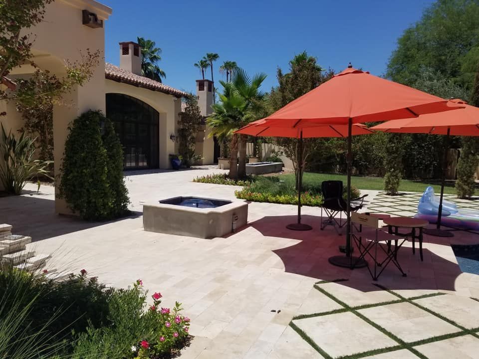 A patio with umbrellas and a hot tub in front of a house